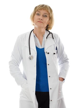 Middle aged woman doctor standing with hands in coat pocket - isolated on white backgroundの写真素材