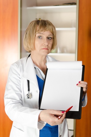 Mature woman doctor holding and showing blank clipboard with space for textの写真素材