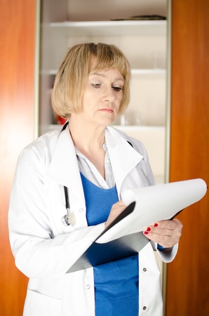 Middle aged woman doctor taking notes in clipboardの写真素材