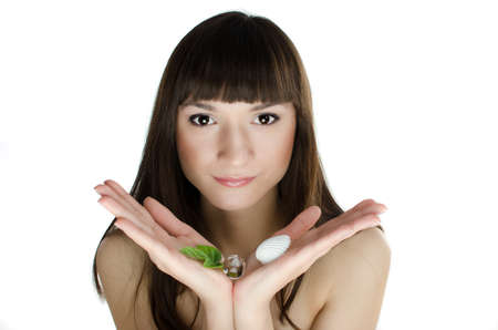 Beautiful girl in spa holding near her face fresh green leaf and shell - isolated on white backgroundの写真素材