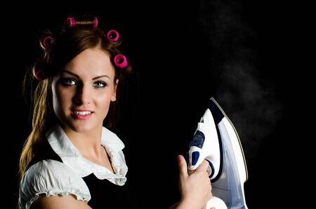 Beautiful woman with curlers on her head holding a steaming ironの写真素材