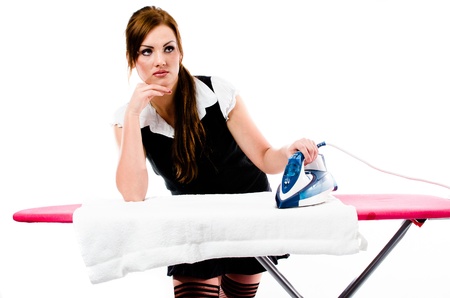 Beautiful brunette woman irons clothes on the ironing boardの写真素材