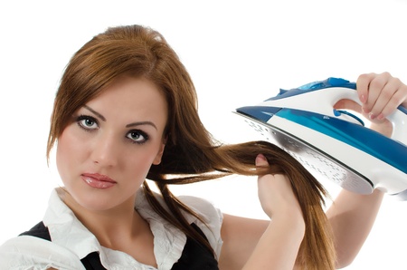 Young woman ironing her hair   isolated on white backgroundの写真素材