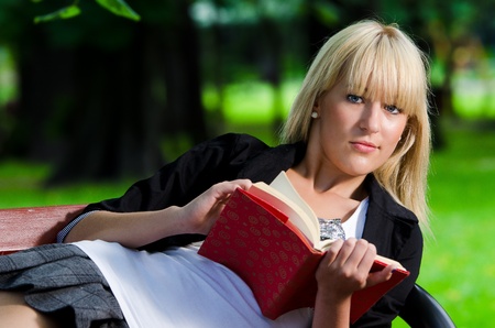 girl lying on a park bench and reading a bookの写真素材