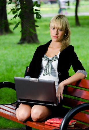 Girl using laptop computer for studying in parkの写真素材