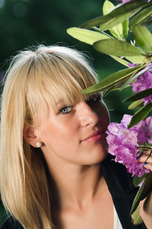 Young blonde woman smelling lilac flower in the parkの写真素材