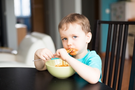 Little baby boy eating bolognese spaghetti for a dinerの写真素材