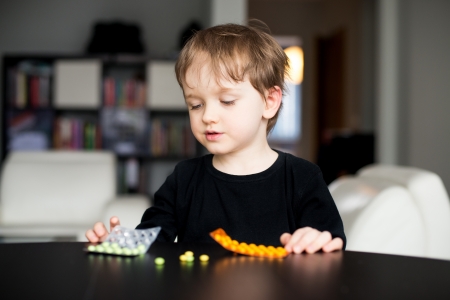 Little boy playing with dangerous medicinesの写真素材