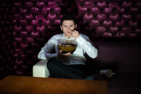 Man watching fascinating program in TV and eating popcornの写真素材