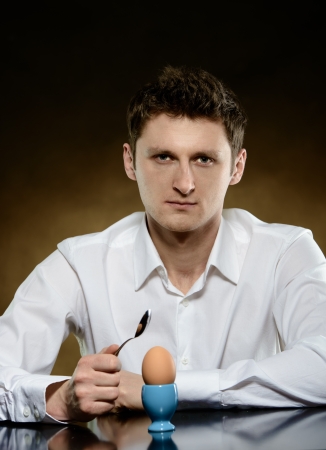 Man opening an egg with a spoon の写真素材