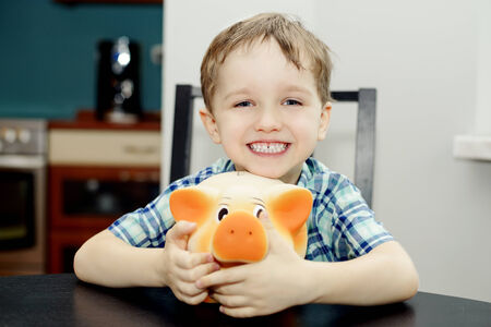 4 year old boy smiling and holding a piggy bankの写真素材