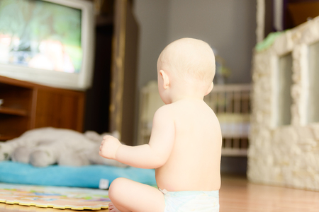 baby watching TV sitting on the floor  in a diaperの写真素材