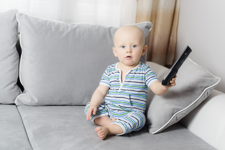 little 6 months baby boy holding tv remote control in handの写真素材