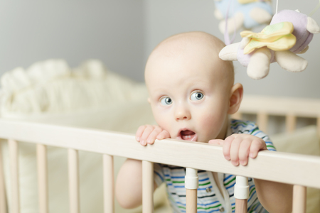 little baby standing  in the crib at his roomの写真素材
