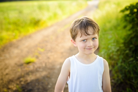 funny little boy on a country road with an innocent expression on his faceの写真素材