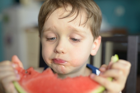 closeup of a child eating watermelon at homeの写真素材