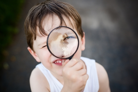 little child  puts a magnifying glass to eyeの写真素材