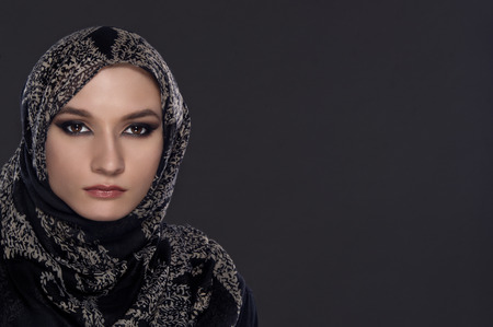 portrait of young beautiful muslim woman with head scarf isolated on gray backgroundの写真素材