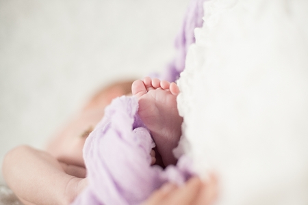 Feet of a baby under the delicate purple blanketの写真素材
