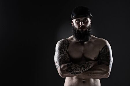 Studio shot of Muscular Man with tattoo  and  baseball cap on dark backgroundの写真素材
