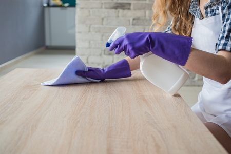 Female hands cleaning table in the living room. On hands protective rubber gloves