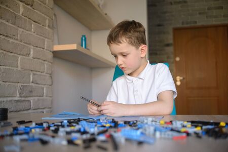 6 years boy playing with technic plastic blocks indoor. Active kid boy having fun with building and...