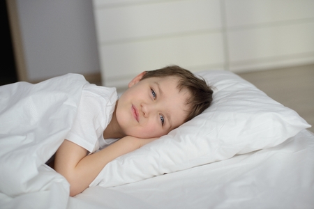 Little boy resting in white bed with eyes open. Sleeping boy. Sleeping childの写真素材