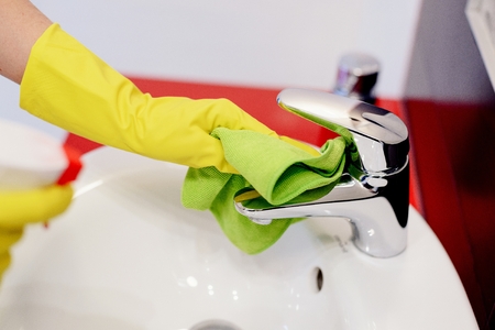 Female hands with rubber protective gloves cleaning tap with green cloth. Spring cleaningの写真素材