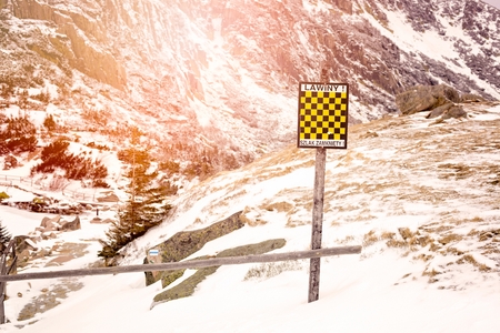 Avalanche sign in winter mountains with snow. Polish inscription Avalanche Danger - Trail Closedの写真素材