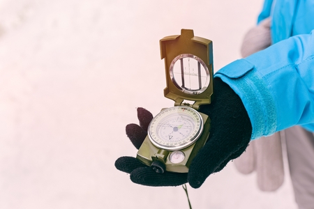 Close up on compass instrument in gloved hand . Mountain hiking trails. Winter mountain trip conceptの写真素材