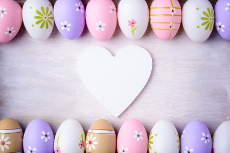 Easter eggs and wooden heart  on a grey wooden background. White wooden heart for room or space for...