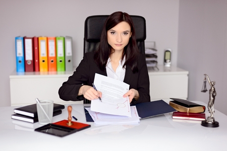 Brunette woman Notary Public indicates the place for signature on notary act . Law office concept.の写真素材