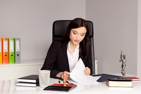 Brunette woman Notary Public reading and signing testament . Law office concept.の写真素材