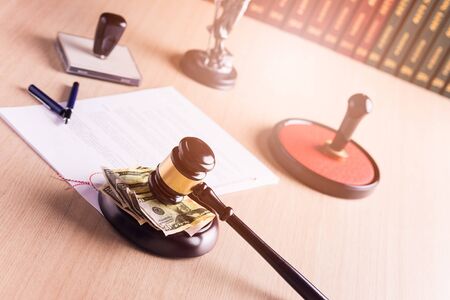 American money under the judge's gavel. Notary public stamper and notary act in the background. Bribe, corruption concept.の写真素材