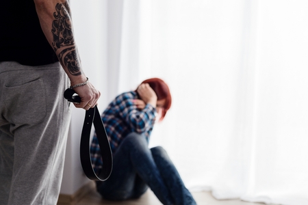 Redhead woman sitting on the floor scared of a husband. Woman is victim of domestic violence and abuse.の写真素材