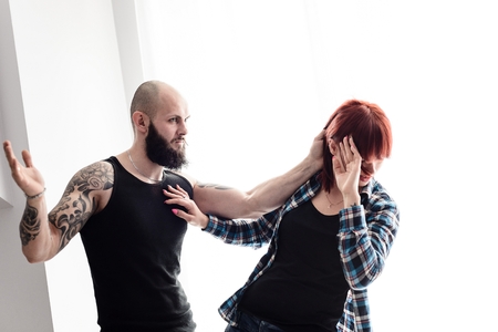 Muscular tattooed man beating up his wife. Domestic violenceの写真素材