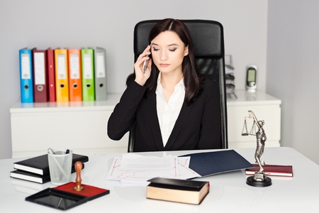 Brunette woman - Notary Public talking on cellphone in her officeの写真素材