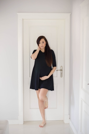 Beautiful brunette 8 months pregnant woman posing in home hall. Dressed in black dressの写真素材