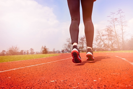 Runner feet running on stadium track closeup - woman running concept. Sunny Dayの写真素材