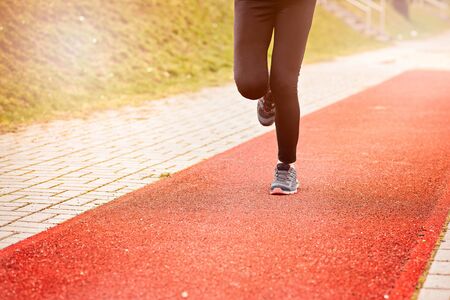 Runner feet running on stadium track closeup - woman running concept. Sunny Dayの写真素材