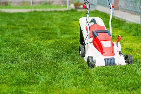 Lawn mower cutting green grass. Work in the garden. Spring gardeningの写真素材