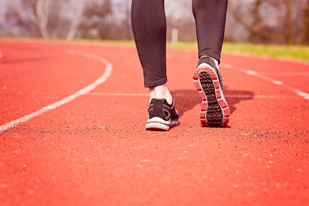 Runner feet running on stadium track closeup - woman running concept. Sunny Dayの写真素材