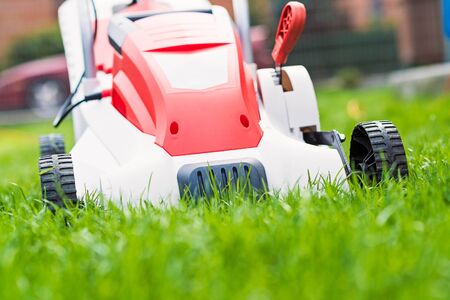 Lawn mower cutting green grass. Work in the garden. Spring gardeningの写真素材