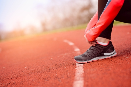 Woman runner tying her shoe - woman running concept. Sunny Dayの写真素材