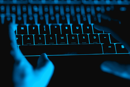Hacker typing on the illuminated  keyboard by night. Internet safety concept.