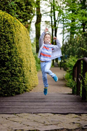 Children's Day. Happy child runs and jumps through the alley in the parkの写真素材