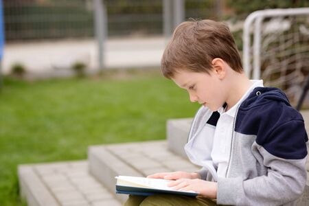 7 year old boy, a student reading a book on the terrace in the gardenの写真素材
