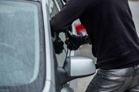 Car thief trying to break into a car with a screwdriver. Car thief, car theft.の写真素材