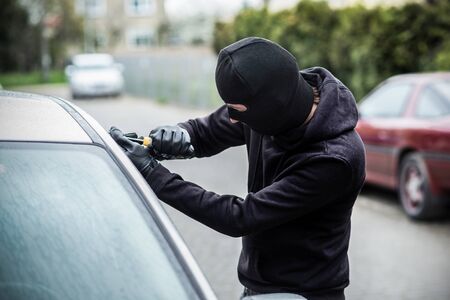 Car thief trying to break into a car with a screwdriver. Car thief, car theft.の写真素材