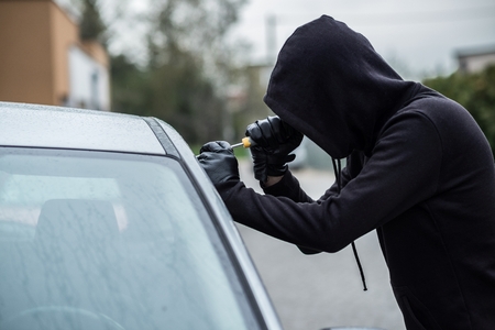 Car thief trying to break into a car with a screwdriver. Car thief, car theft.の写真素材